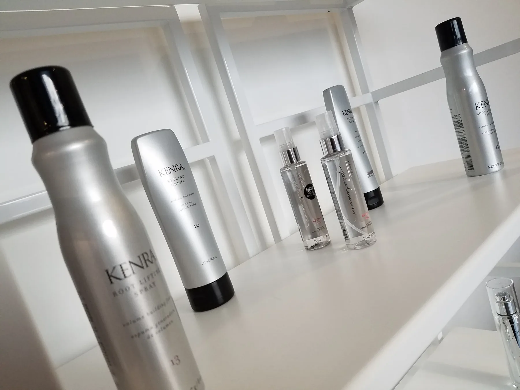 Professional Kenra styling products lined up on a white shelf.